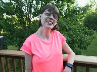 Stephanie smiling while leaning against a deck railing.